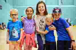 Group photo of children smiling in a sports hall