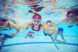 Group photo of children smiling under water in a swimming pool