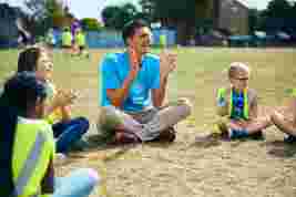 JAG staff and children sat in a circle on a field