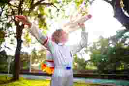 Child playing with a rocket outside wearing a astronaut jumpsuit