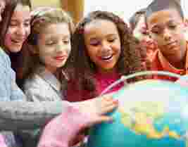A group of children smiling and examining a globe, engaging in a learning activity together.