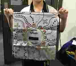 Person holding a drawstring bag decorated with colorful Aboriginal-style art and a blank "Name" label in the center.