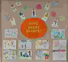 Bulletin board with drawings of various safety workers like police officers and doctors, asking "Who Keeps Us Safe?" with children's art.