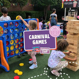 Children playing giant Connect Four and Jenga at a summer camp carnival event. A popcorn stand and bunting are visible in the background.