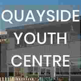 Exterior of Quayside Youth Centre with large text overlay. White building, clear sky, and fences visible.