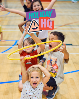 Children playfully posing with a yellow hoop indoors, excited expressions. Holiday HQ logo overlay.