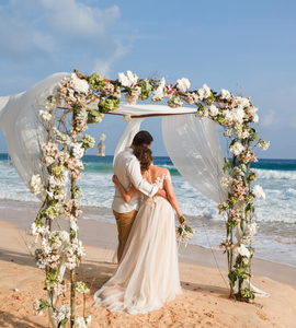 Novomanželé pod svatebním obloukem na pláži