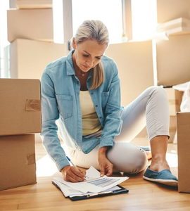 Žádost o hypotéku krok za krokem - krabice, obývák, žena vyplňuje formulář