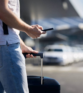 Muž na letišti s kufrem a telefonem, který používá