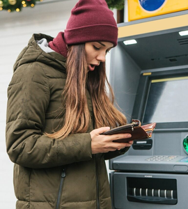 Kreditní karta: ztráta nebo odcizení - mladá žena před bankomatem, otevřená peněženka