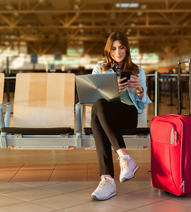 Žena na letisku s počítačom, mobilom a batožinou