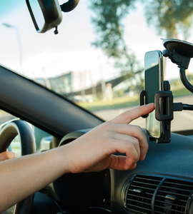 Muž ovládá telefon na držáku v autě