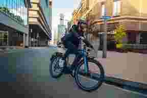 Man met helm op e-bike rijdt in bocht in de stad