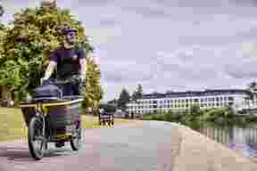 Man riding Raleigh Stride 2 electric cargo bike near river
