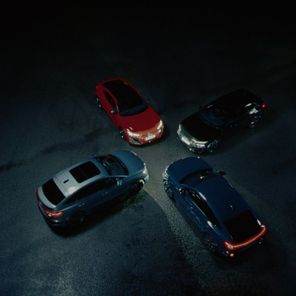 Four Audi cars facing each other in a circle in the dark with headlights on