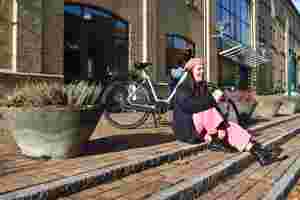 a-SHINE elcykel parkeret og foran sidder pige med lyserøde bukser på et trappetrin