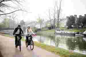 Two people biking next to a canal