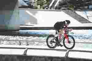 Road cyclist biking on the Lapierre time-trial Aerostorm DRS bike across a bridge