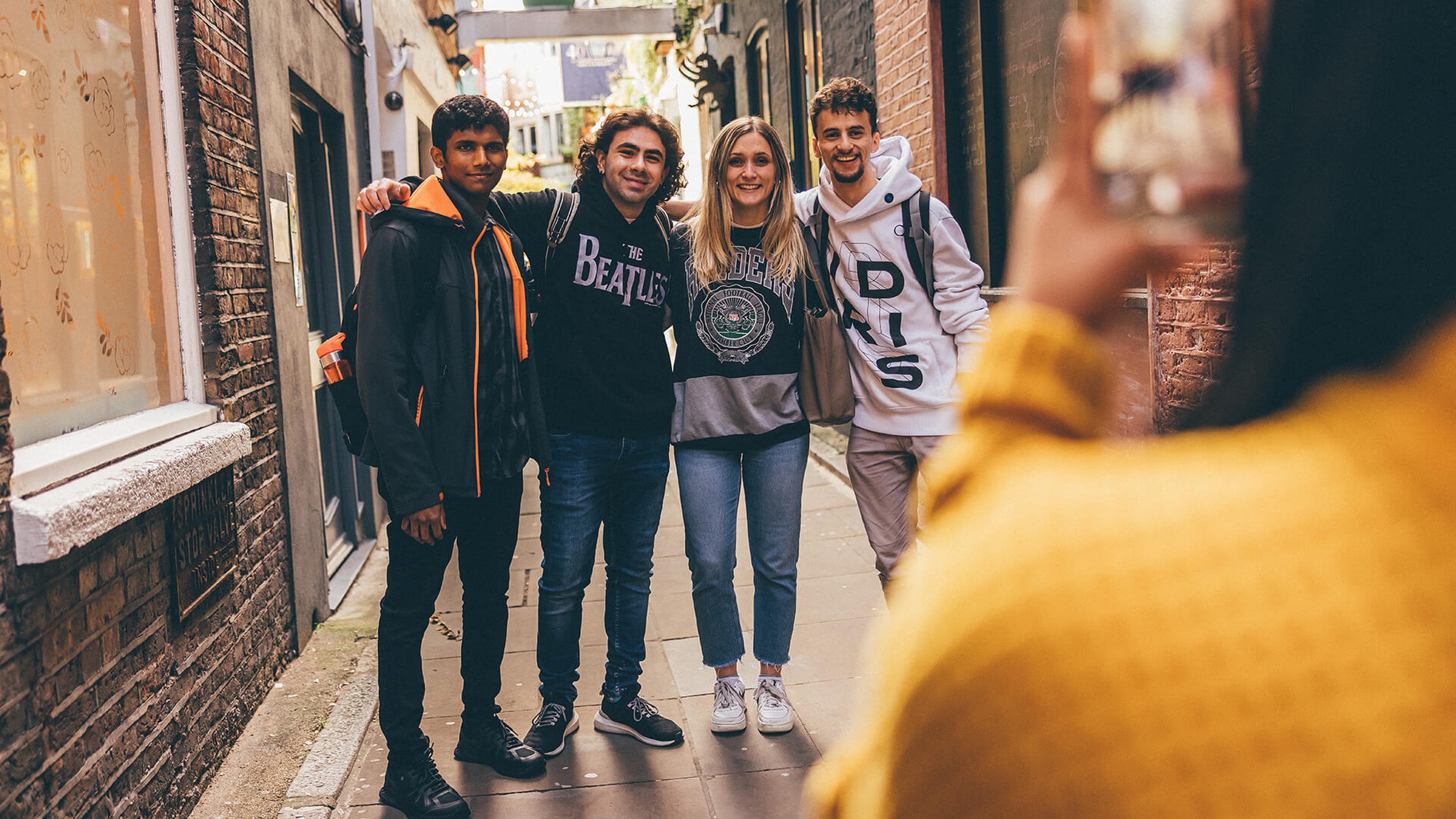 Four students having their photo taken in alleyway