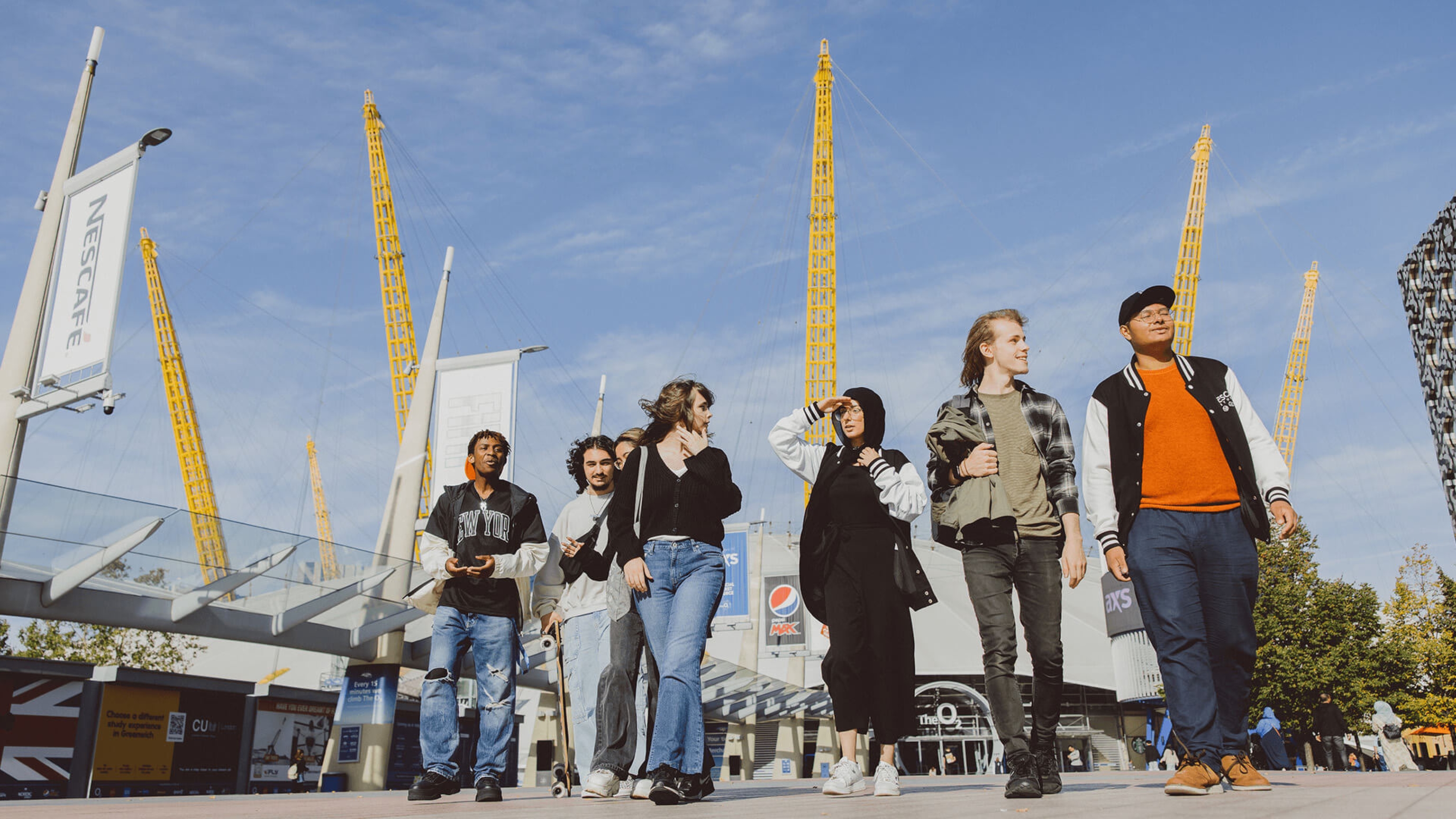 Group of students walking through North Greenwich with O2 arena in background