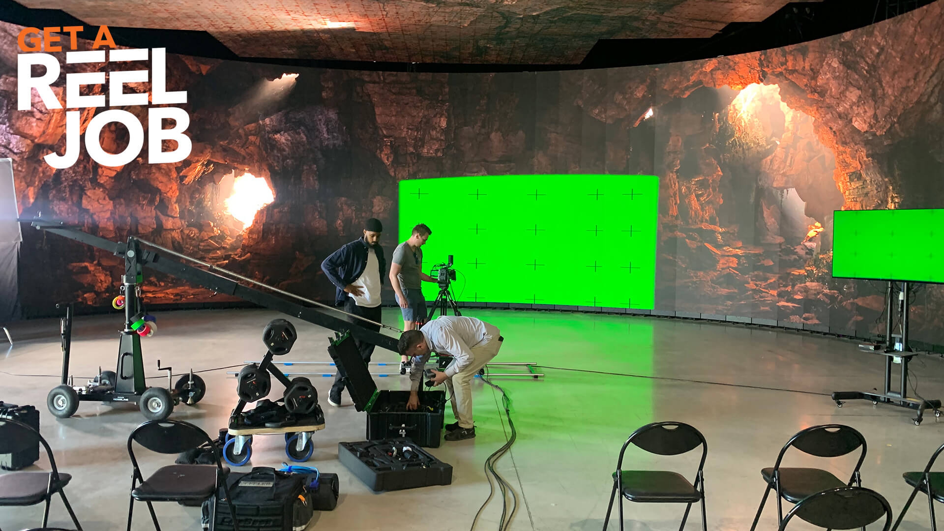 Scene from a virtual production set up with a cave on a green screen. Logo reads: Get a REEL Job.