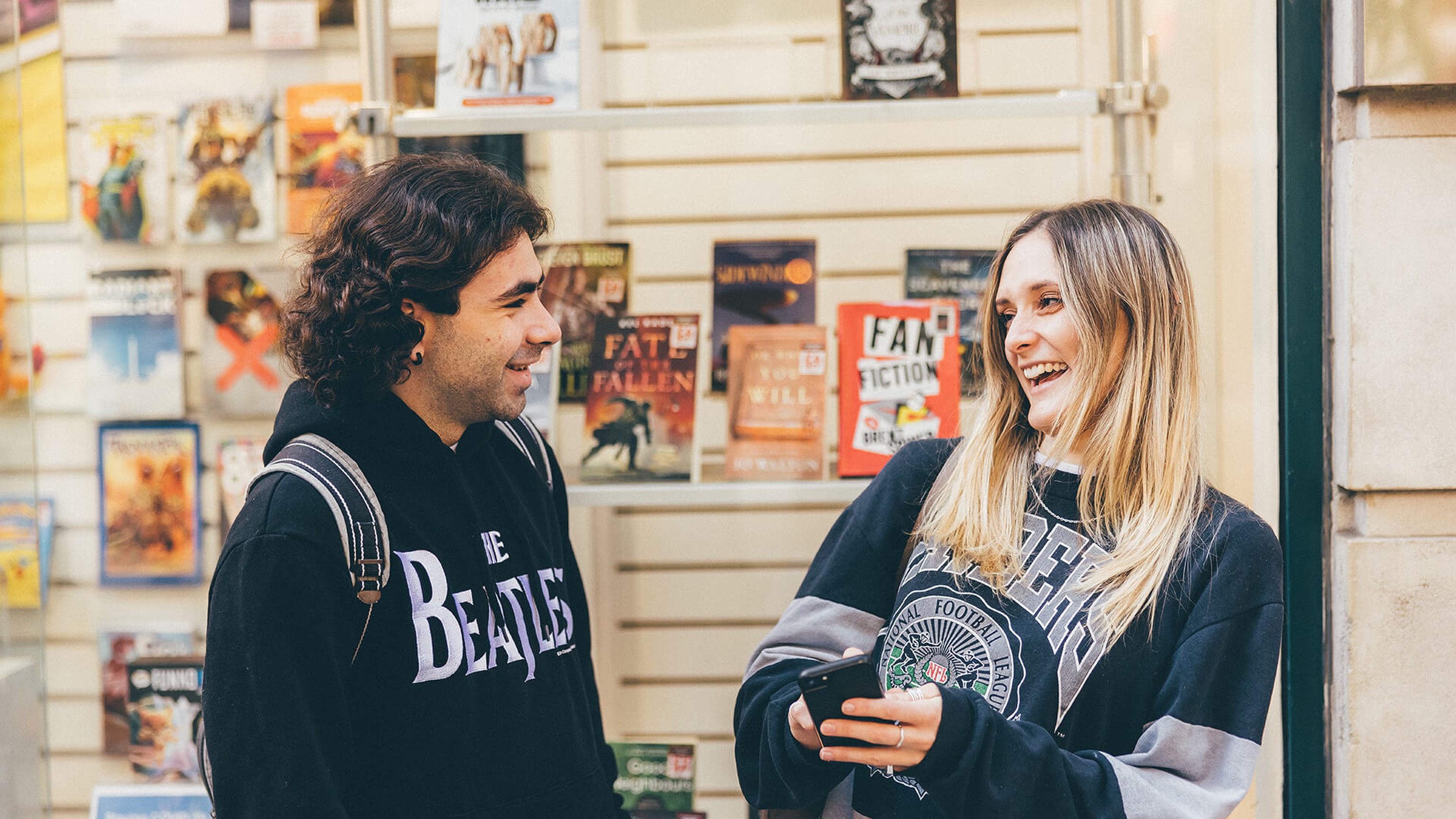 Two students laughing outside a shop