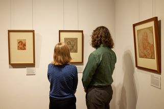 Zwei Personen sind von hinten zu sehen wie sie drei Kunstwerke betrachten