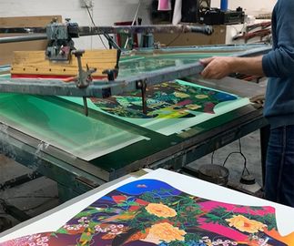 print workshop applying varnish highlights to the surface of a colourful screenprint