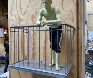 half-clothed resin figure on dark silver metal balcony, photographed in workshop