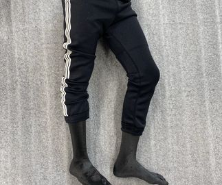 miniature model legs wearing black tracksuit bottoms, resting on grey foam sheet
