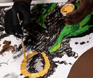 Khari Turner adding gold paint to a circle of an earring