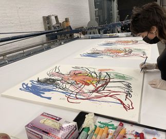 Cristina signing her print next to pastels in studio