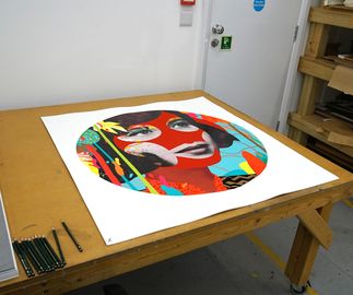 in production shot of a circular print of a woman's face with red glitter by Paul Insect