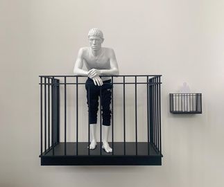 small and large versions of a man on balcony sculpture mounted alongside one another on wall