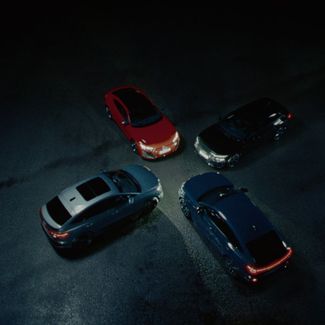 Four Audi cars facing each other in a circle in the dark with headlights on
