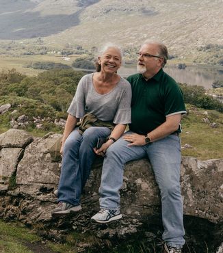 couple of travelers sitting a on a rock in ireland together