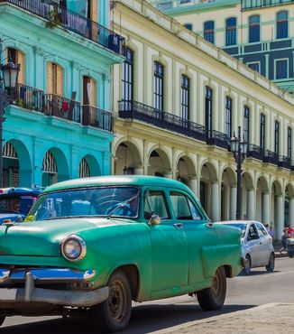 Old cars driving through vibrant Cuba