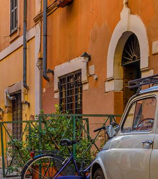white italian car parked on a cobblestone street in trastever rome