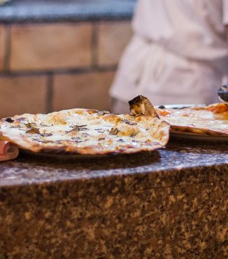 five italian pizzas on a granite shelf in a kitchen