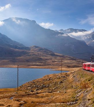 red cable car train riding next to a lake in switzerland