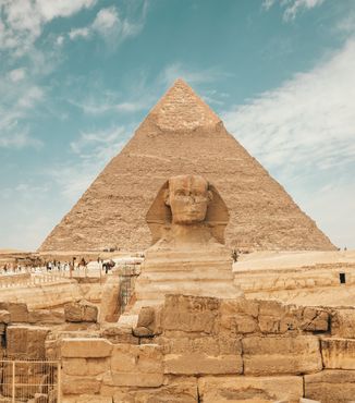 people walking around the pharaoh sculpture in front of the pyramids in egypt