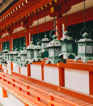 green chinese lanterns hanging from red kasuga taisha shrine in japan