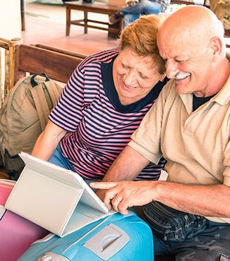 two elderly people looking at an ipad near some suitcase