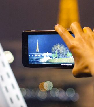 close up of hand holding a camera taking a photo of the eiffel tower