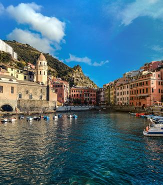 boats in the marina with people walking along wall in cinque terre italy