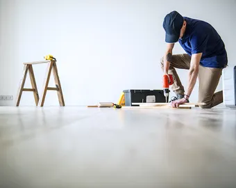 Un homme rénove le parquet de son appartement locatif