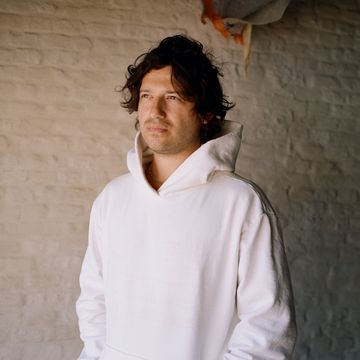 David Rudnick wearing a white hoodie, gazing pensively into the middle distance.