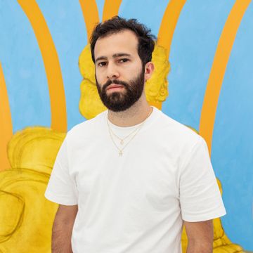 Nicasio Fernandez standing in front of a bright yellow painting