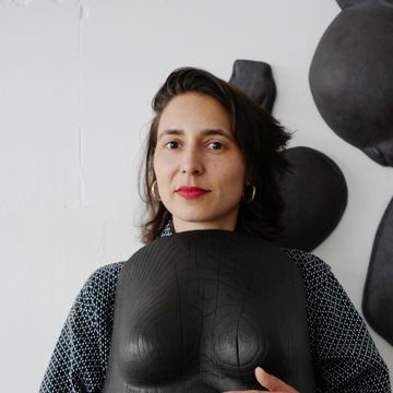 Artist Prune Nourry holding a sculpture to her chest