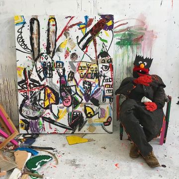 Person in red furry disguise sitting next to large abstract painting
